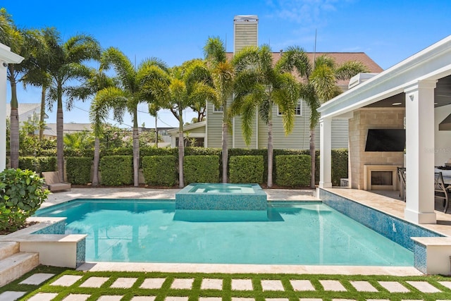 view of pool with a patio area, an outdoor fireplace, a fenced backyard, and a pool with connected hot tub