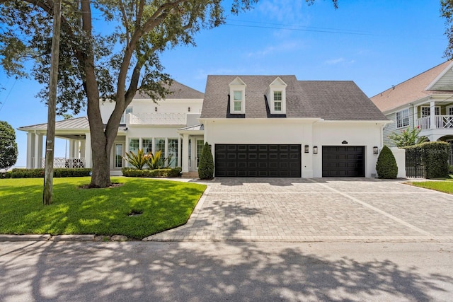 view of front of house with decorative driveway, roof with shingles, stucco siding, a front yard, and a garage