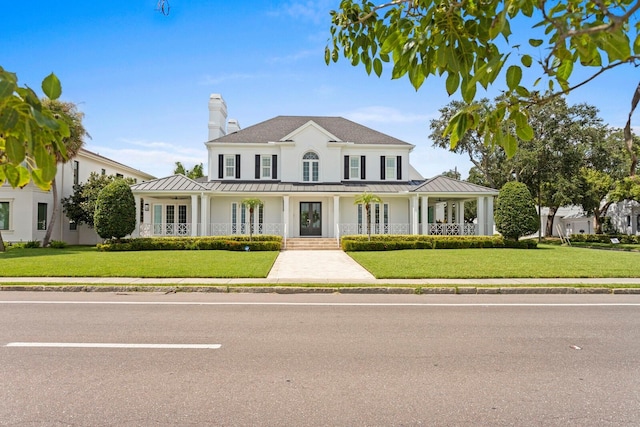 view of front facade with a standing seam roof, metal roof, a front lawn, and covered porch