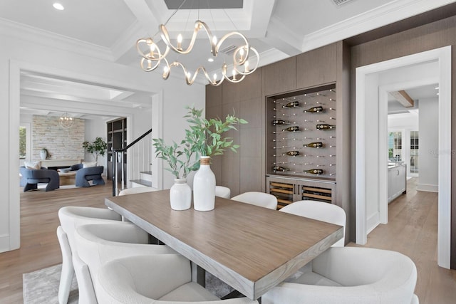 dining space with light wood-style flooring, ornamental molding, and beam ceiling