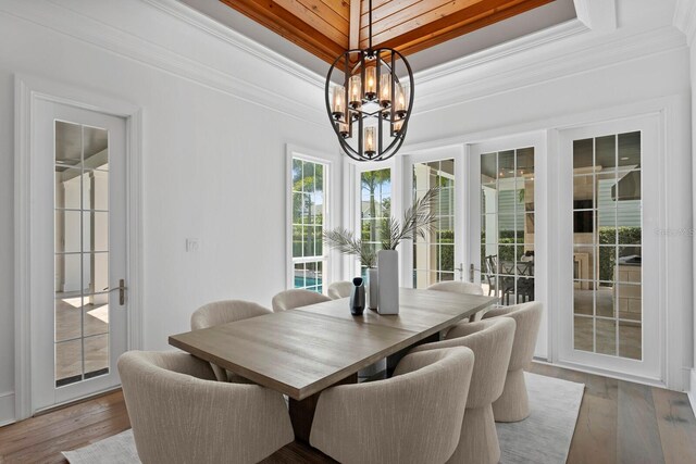 dining space with ornamental molding, a tray ceiling, hardwood / wood-style floors, and an inviting chandelier