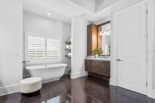 bathroom with baseboards, a soaking tub, marble finish floor, vanity, and recessed lighting