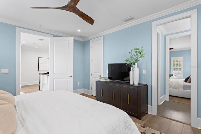 bedroom with crown molding, visible vents, ceiling fan, wood finished floors, and baseboards