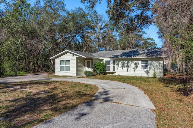 ranch-style home with driveway and a front lawn