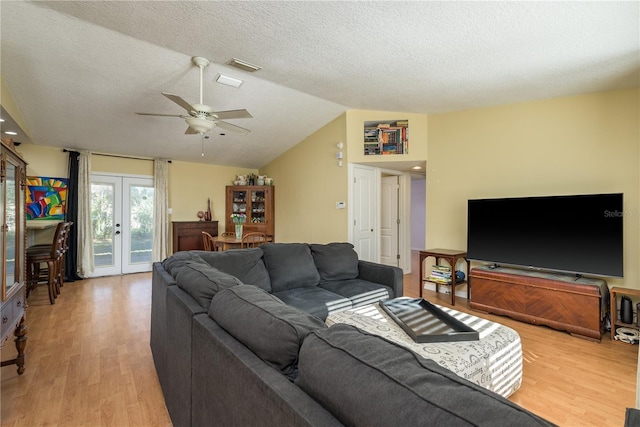 living room with lofted ceiling, light wood finished floors, visible vents, and french doors