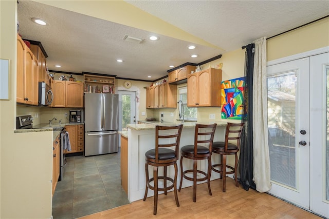 kitchen featuring light stone counters, french doors, appliances with stainless steel finishes, a textured ceiling, and a peninsula