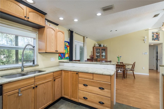 kitchen with a peninsula, visible vents, a sink, and lofted ceiling