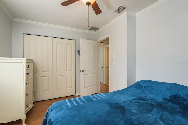 bedroom with ornamental molding, a closet, wood finished floors, and visible vents