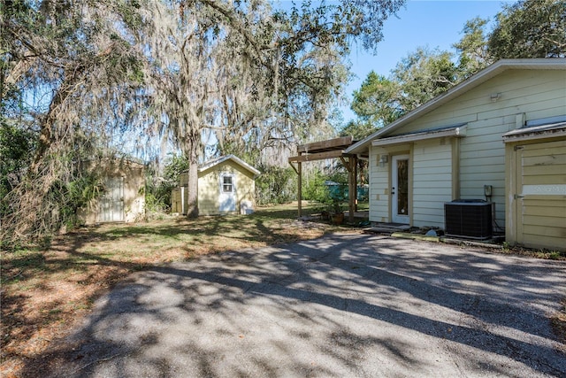 view of front of home featuring driveway, a shed, an outdoor structure, and cooling unit