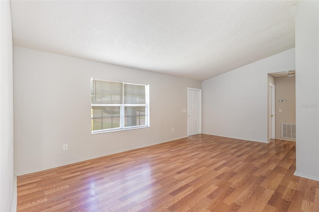 unfurnished room with light wood finished floors, visible vents, and a textured ceiling