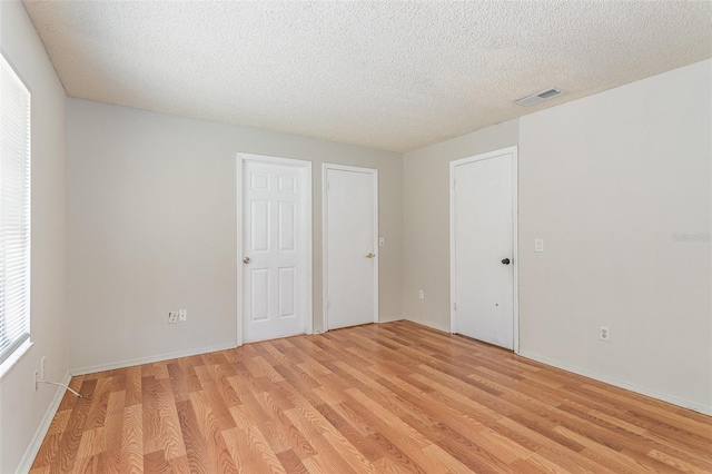 unfurnished bedroom with visible vents, a textured ceiling, and light wood finished floors