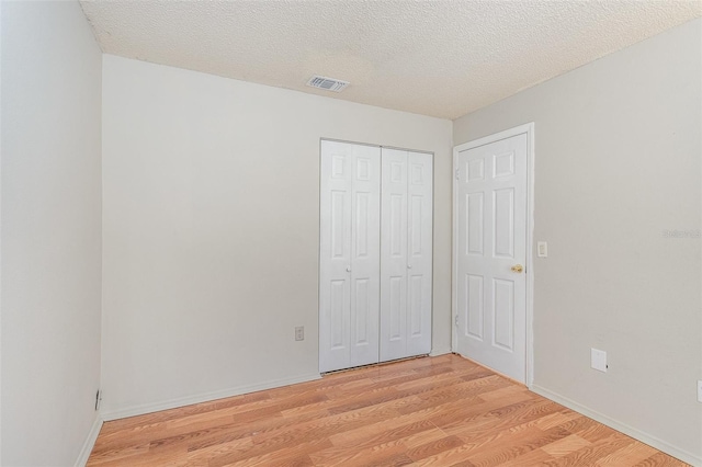 unfurnished bedroom with light wood finished floors, baseboards, visible vents, and a textured ceiling