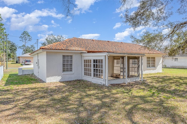 rear view of property featuring a yard, a tiled roof, and stucco siding