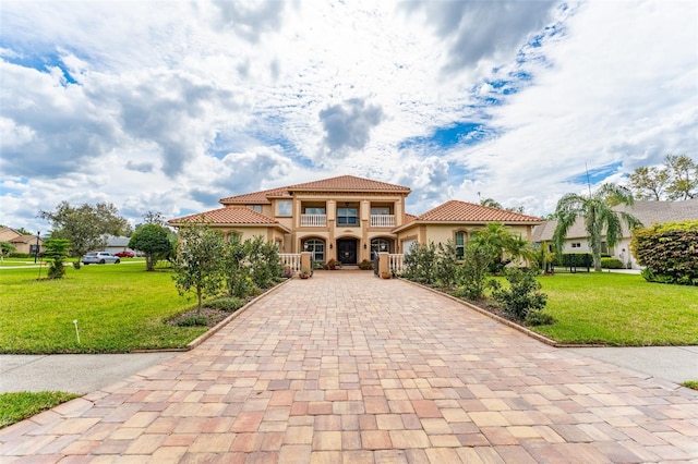 mediterranean / spanish house with stucco siding, a front lawn, decorative driveway, and a tiled roof