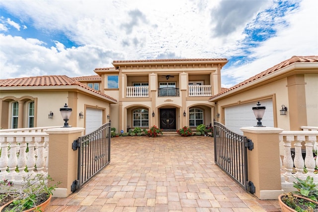 mediterranean / spanish-style house with a balcony, an attached garage, and a gate