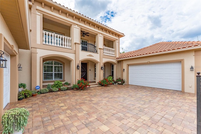 mediterranean / spanish house with a garage, decorative driveway, a balcony, and stucco siding