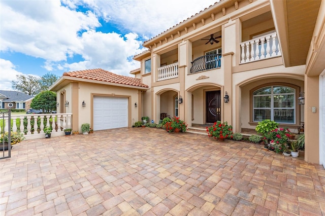 view of front of home with decorative driveway, stucco siding, a balcony, a garage, and a tiled roof