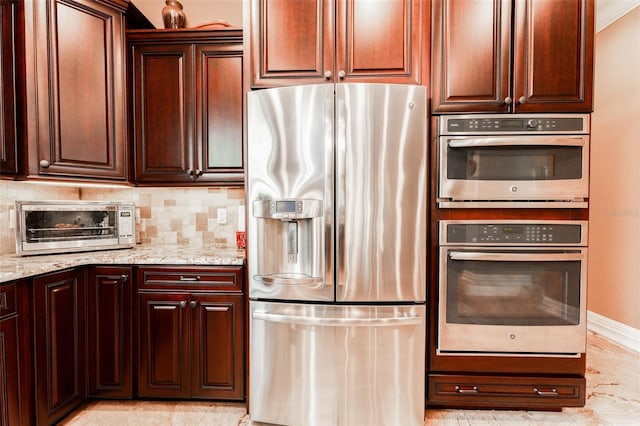 kitchen featuring a toaster, decorative backsplash, appliances with stainless steel finishes, light stone countertops, and baseboards