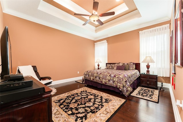 bedroom featuring baseboards, a ceiling fan, dark wood-type flooring, a tray ceiling, and crown molding