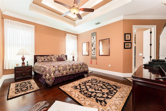 bedroom with dark wood-style floors, a raised ceiling, multiple windows, and ornamental molding