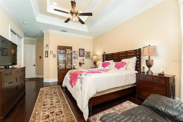 bedroom with visible vents, baseboards, ornamental molding, dark wood-style floors, and a tray ceiling