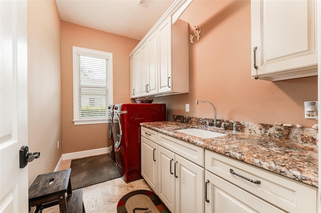 clothes washing area with separate washer and dryer, a sink, cabinet space, and baseboards