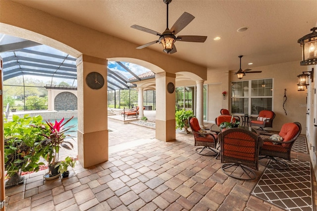 view of patio / terrace featuring glass enclosure, ceiling fan, and outdoor lounge area