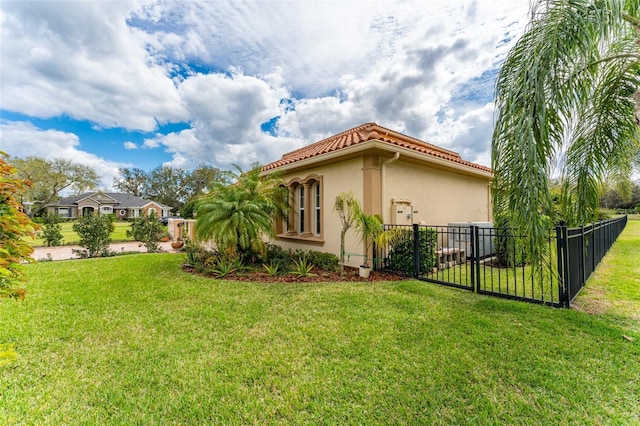 view of home's exterior featuring a yard, fence, a tile roof, and stucco siding