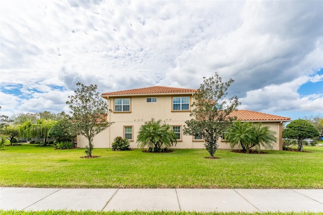 view of front of property featuring stucco siding, a front lawn, and a tiled roof