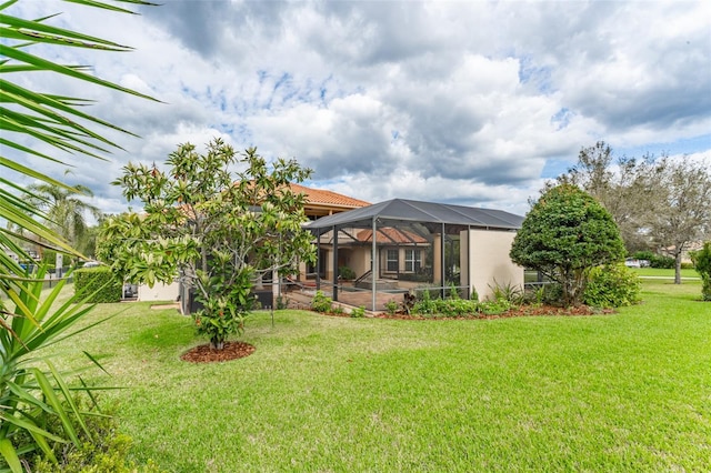 rear view of property featuring a lanai, a patio area, a yard, and stucco siding