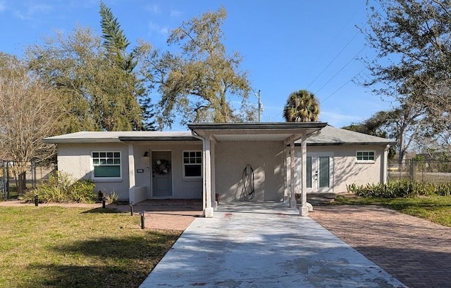 view of front of house with decorative driveway, a front yard, fence, and stucco siding