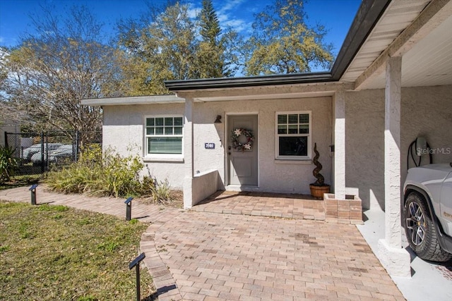 property entrance featuring fence and stucco siding