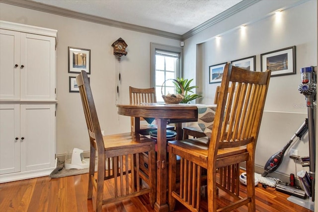 dining room featuring a textured ceiling, wood finished floors, and crown molding