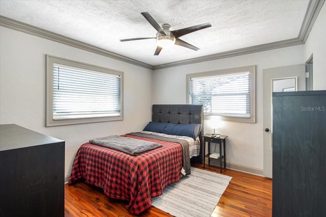 bedroom with crown molding, a textured ceiling, baseboards, and wood finished floors