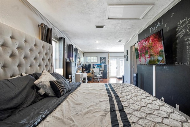 bedroom featuring attic access, ornamental molding, and a textured ceiling