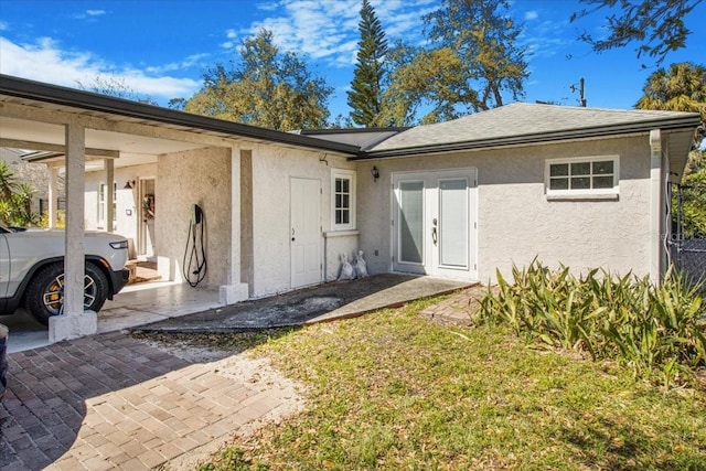 rear view of property with a shingled roof, french doors, and stucco siding