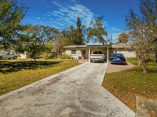 single story home featuring driveway, a carport, and a front yard