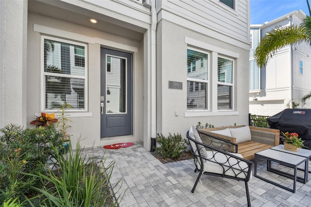 property entrance with outdoor lounge area, a patio area, and stucco siding