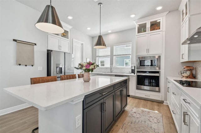 kitchen featuring appliances with stainless steel finishes, light wood finished floors, white cabinetry, and hanging light fixtures