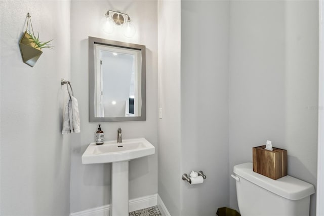 half bath featuring baseboards and toilet