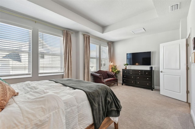 bedroom featuring a tray ceiling, a textured ceiling, light colored carpet, visible vents, and baseboards