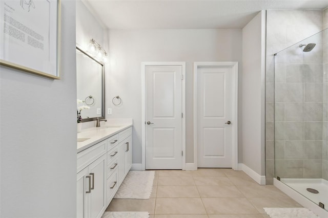 full bath featuring tiled shower, double vanity, a sink, and tile patterned flooring