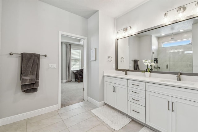 bathroom with a shower stall, double vanity, a sink, and tile patterned flooring