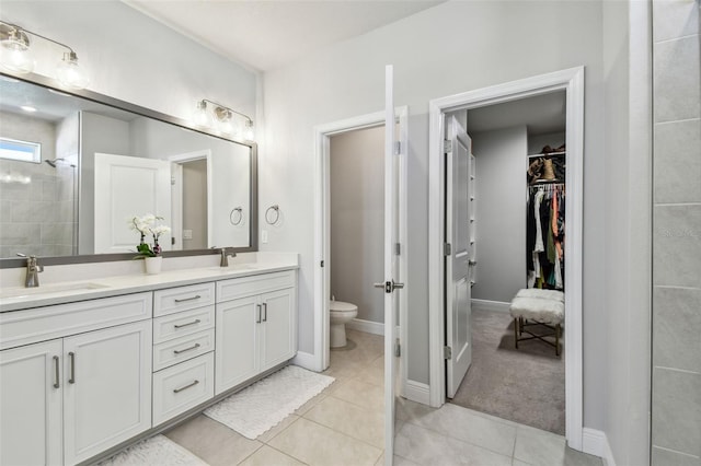 bathroom featuring a sink, toilet, a walk in closet, double vanity, and tile patterned flooring