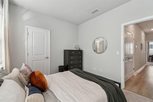 bedroom featuring visible vents, baseboards, attic access, and light wood-style floors