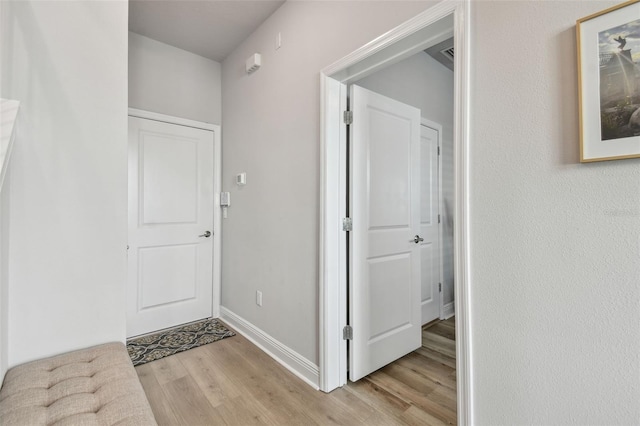 hall featuring baseboards and light wood-type flooring