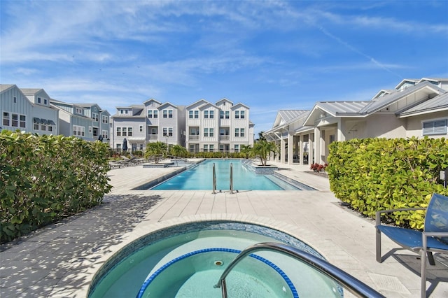 pool featuring a residential view, a patio, and a hot tub