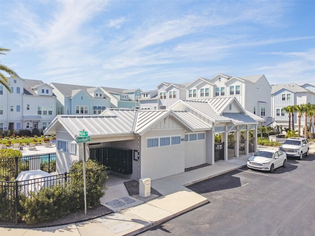 view of property featuring a residential view, a standing seam roof, fence, and metal roof