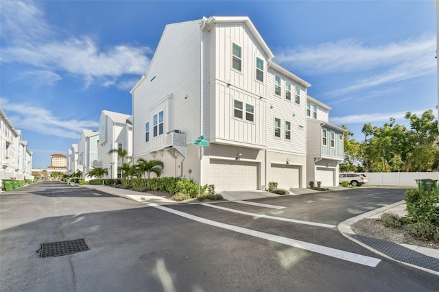 exterior space featuring a garage, a residential view, driveway, and fence