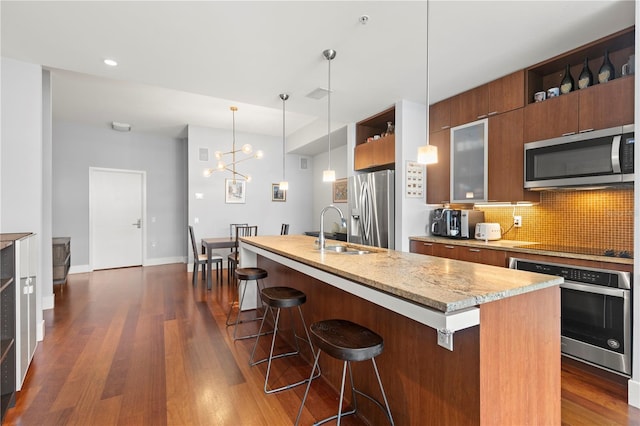 kitchen with dark wood-style floors, a breakfast bar area, tasteful backsplash, appliances with stainless steel finishes, and a sink